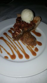 Pecan pie with a scoop of vanilla bean ice cream and pecan praline